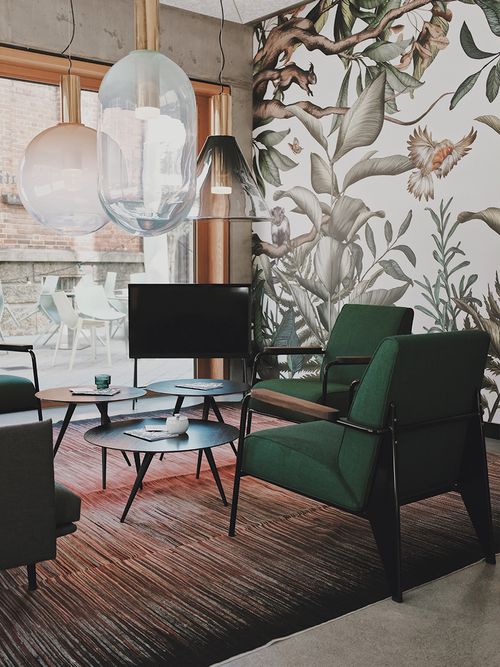 Zwei grüne Sessel vor einer floralen Tapete.