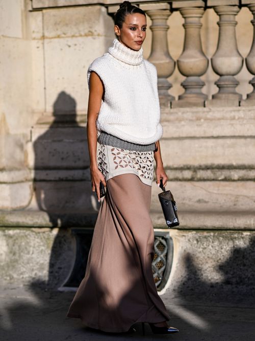 A guest is seen wearing a white Louis Vuitton sweater, pink skirt and brown Louis Vuitton handbag outside the Louis Vuitton show during Womenswear Spring/Summer 2025 as part of Paris Fashion Week on October 01, 2024 in Paris, France.