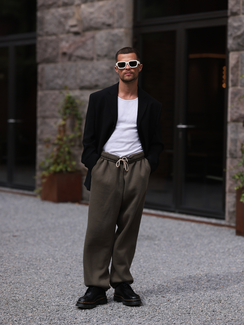 Kevin Elezaj trägt einen schwarzen Blazer, weißes T-Shirt, braune Jogginghose und Combat Boots auf der Copenhagen Fashion Week.