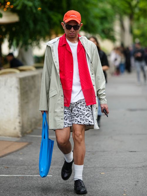Ein Gast auf der Paris Fashion Week trägt einen Regenmantel als stylische Übergangsjacke