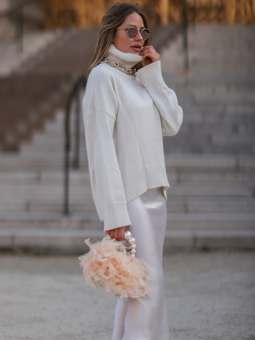 Influencerin Ginta Biku trägt eine auffällige Statementkette über einen weißen Rollkragenpullover und Rock mit auffälliger Tasche aus Perlen und Tüll in Paris