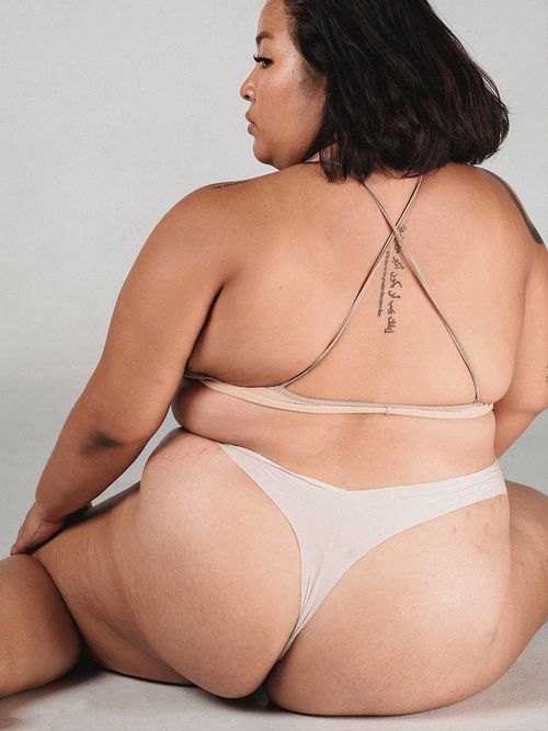 Rückenansicht einer sitzenden Frau mit hautfarbener Unterwäsche