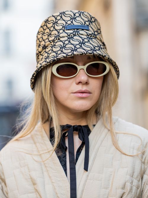 Joicy Muniz trägt einen Bucket Hat mit Sonnenbrille und eine beige Jacke auf der Paris Fashion Week.
