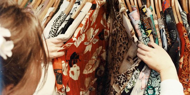 Eine Frau die durch einen Kleiderständer voller Vintage-Hemden stöbert.