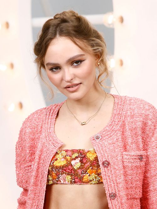 Lily Rose Depp in einem rosa Chanelblazer zu einem bunten Bustiertop.
