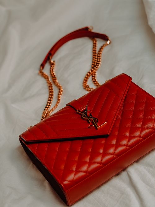 Rote Tasche von YSL liegt auf einem weißen Bettlaken.