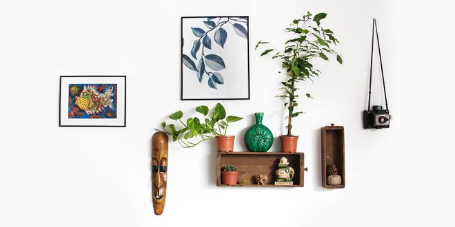 Weiße Wand mit vielen kleinen Urlaubserinnerungen und Pflanzen.