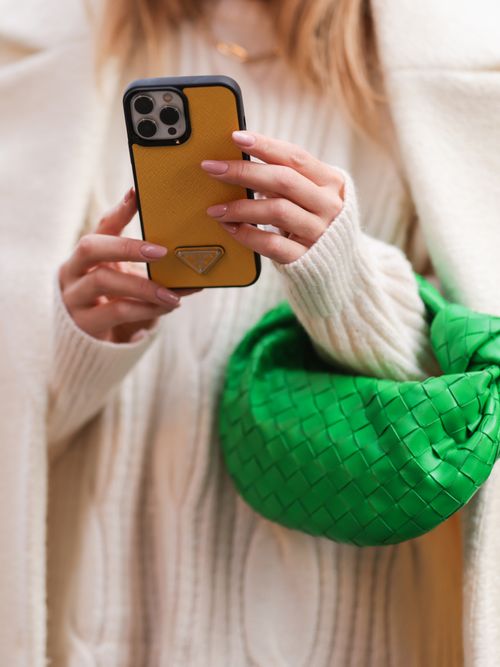 5 affordable bags to hold you over until Black Friday sales, woman in white sweater holding green bottega veneta bag