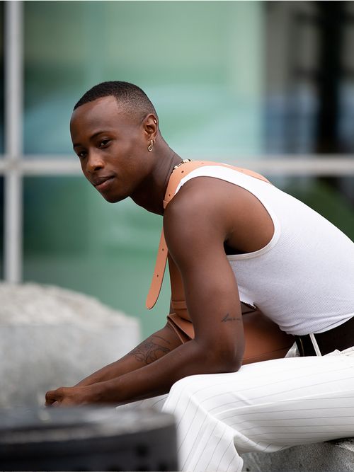 Mann mit weißem Tank Top und Nadelstreifhose und multiple Earrings.