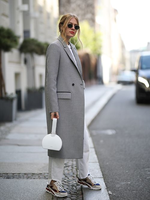 ragazza con cappotto a quadri e jeans bianchi