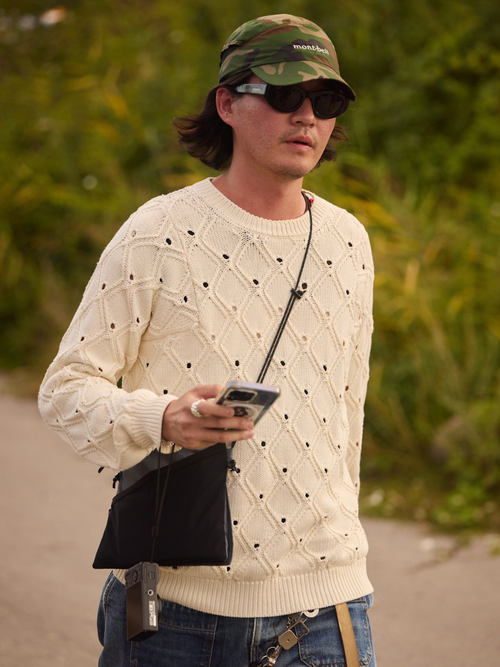 A guest wears a camo baseball cap and a beige sweater