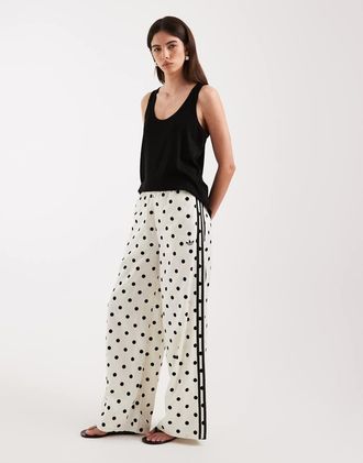 adidas Originals pantaloni sportivi in raso a gamba larga con stampa a pois bianchi-Bianco