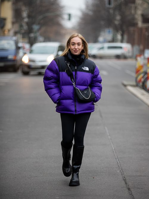Sonia Lyson in einer schwarzen Leggings und einer Daunenjacke von The North Face