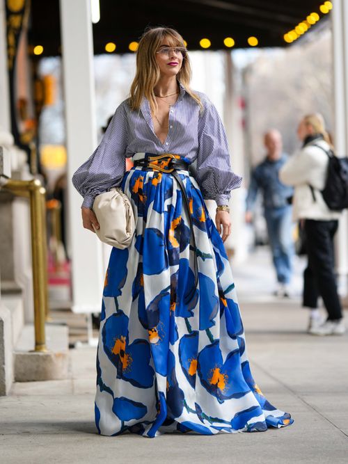 Street Style Look von der New York Fashion Week, wo ein Gast eine blau gestreifte Hemdbluse mit Maxirock im Blumenmuster trägt.