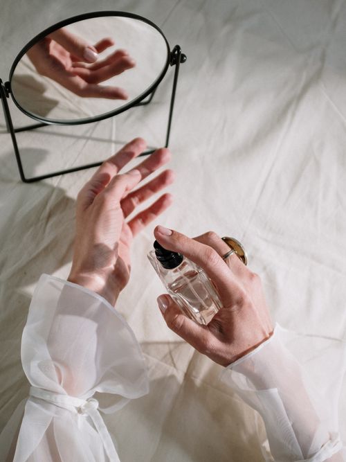 Close-up von einer Frau, die sich ihr Parfum aufsprüht in einem schönen Still Life-Setting