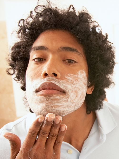 Ein Mann trägt gerade einen Rasierschaum im Gesicht auf.