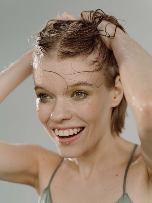 Frau mit nassen Haaren und einem grünen Spaghettitop.