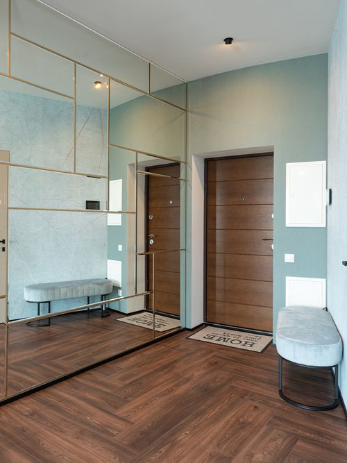 Ein Flur mit einer ovalen Samtbank und einer kompletten Spiegelwand.