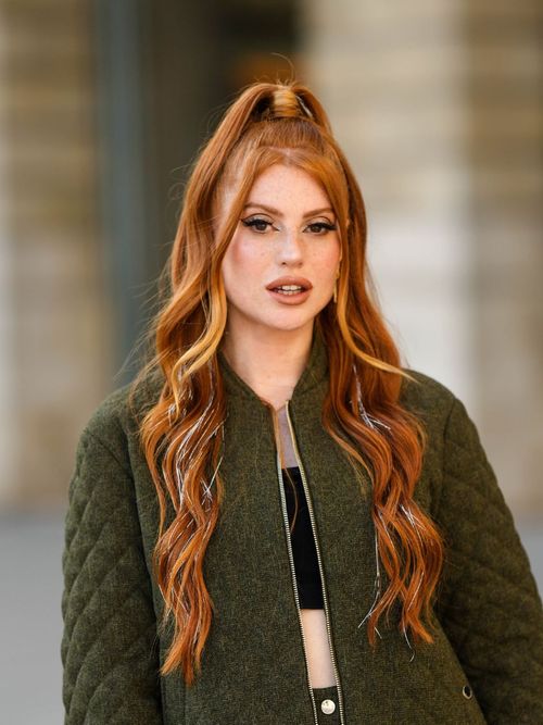 Fiona Oslo trägt eine grüne Bomberjacke mit Hotpants und cropped Top in Schwarz. Sie trägt ihre Haare jetzt in Kupfer Farben.