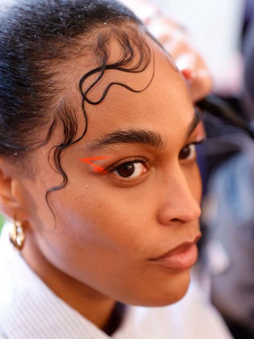 Model dass gerade einen orangefarbenen Eyeliner bekommt.
