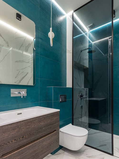 Badezimmer mit holzfarbenen Waschtisch und blauen Fliesen.