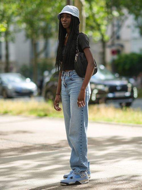 Streetstyle mit einer Jeans und Sneakers zu einem schwarzen Top und einem Bucket Hat.