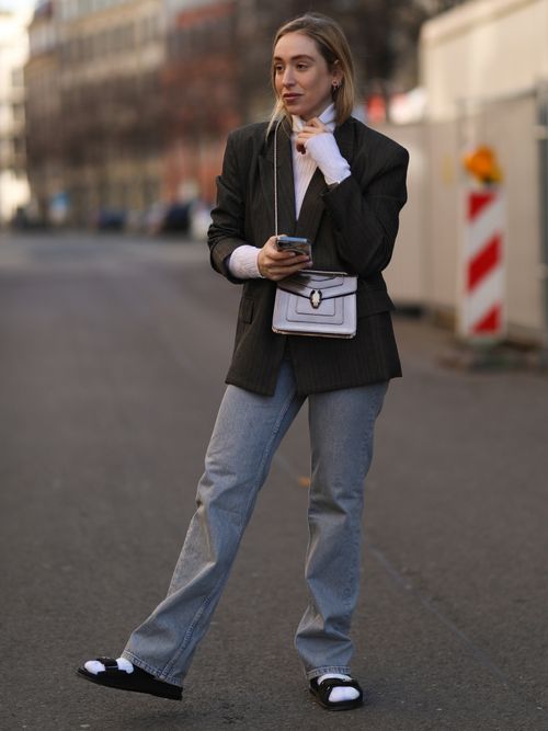 BERLIN, GERMANY - FEBRUARY 21: Sonia Lyson wearing Chanel black sandals, Nike tie dye socks, Zara blue jeans, The Frankie Shop grey blazer, white Lala Berlin turtleneck, Bulgari bag and watch on February 21, 2021 in Berlin, Germany. (Photo by Jeremy Moeller/Getty Images)