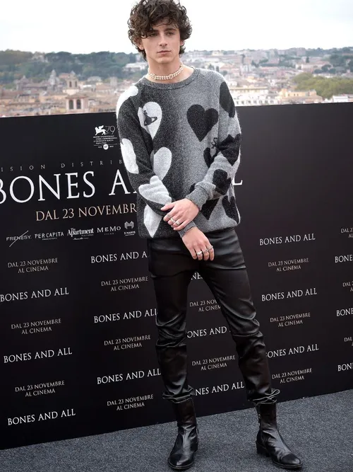 Timothée Chalamet bei einer Premiere und trägt einen grauen Pullover mit Herzmotiv und schwarzer Lederhose.