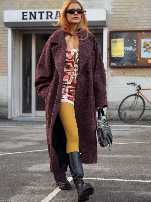 Streetstyle mit einer gelben Strumpfhose, einem gehäkelten Overall und einem dunkelroten Mantel.