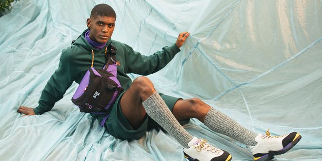 Mann mit grauen Strümpfen und Wanderschuhen liegt in einem türkisen Paragleiter.