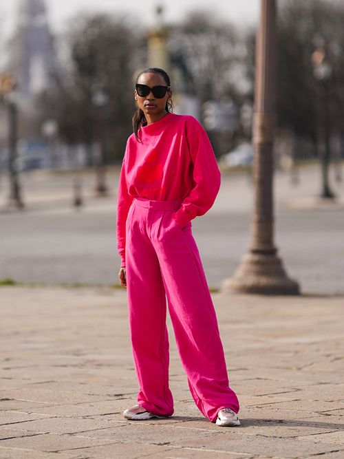 Streetstyle mit knalliger pinker Hose und Pullover zu weißen Sneakers.