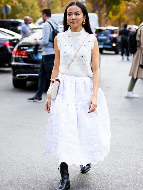 Junge Frau trägt weißen Pullunder mit weißen Rock und schwarzen Boots.