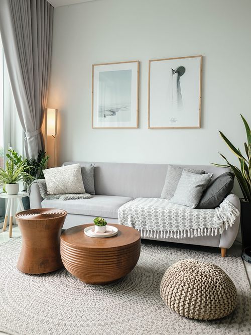Graues Sofa, zwei Beistelltische aus Holz und ein gehäkelter Pouf.