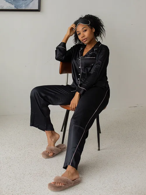 Frau auf einem Stuhl in einem Pyjama und Fellschlappen.