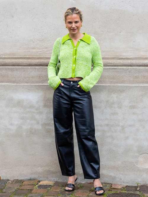 Mija Knezevic trägt einen grünen Strickpulli mit schwarzer Lederhose und Sandaletten auf der Copenhagen Fashion Week.
