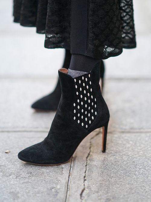 Close up von Chelsea Boots mit Absatz in schwarz zu einem transparenten Rock.
