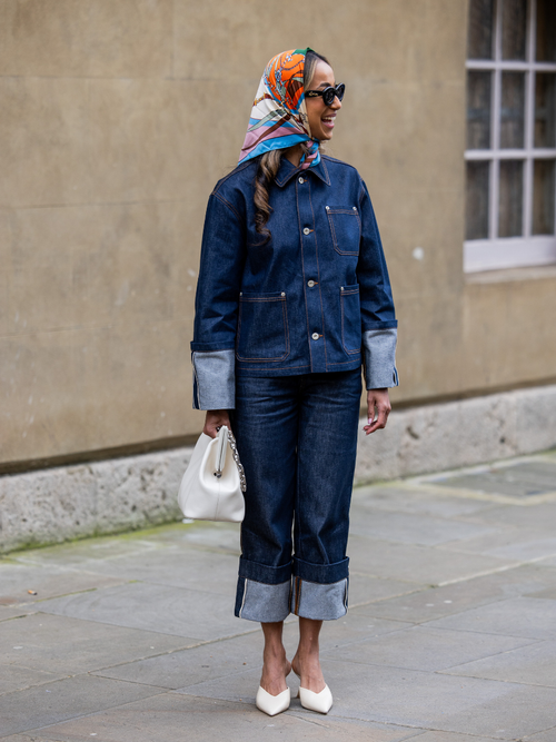 A guest wears a denim jacket and jeans with a silk scarf and sunglasses