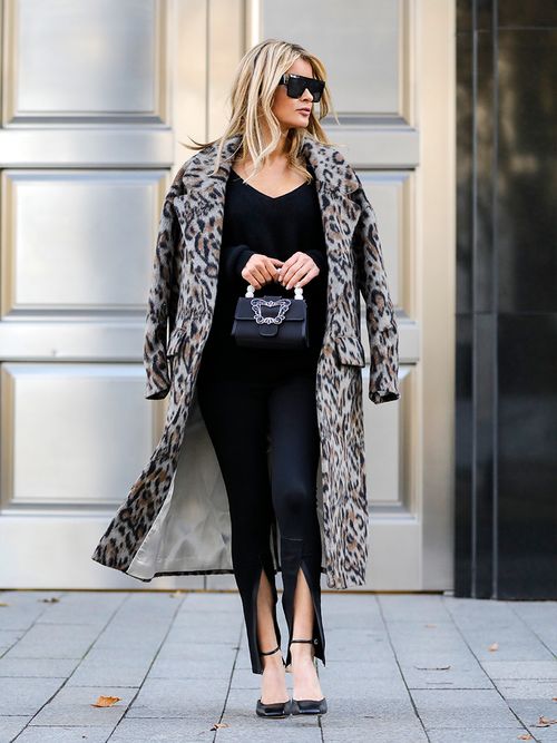 Gitta Banko in einem schwarzen Look mit einem Mantel in Animal-Print.