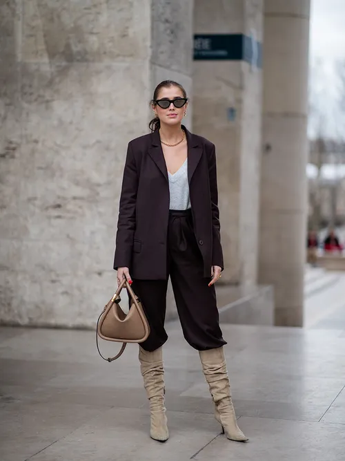Darja Barannik trägt einen schwarzen Hosenanzug mit Wildlederstiefel in Paris.