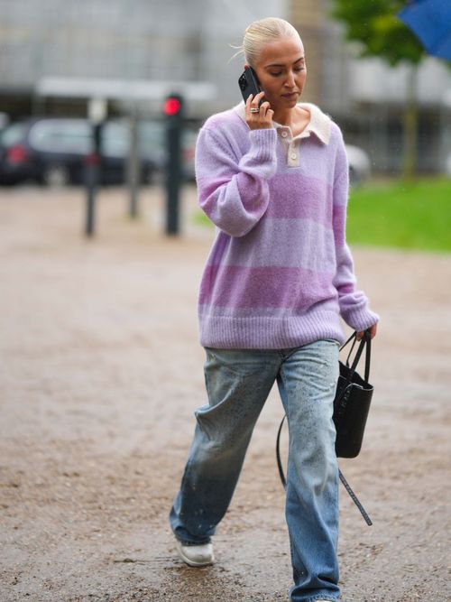 Street Style Look von der Copenhage Fashion Week, wo ein Gast ein gestreiftes Poloshirt mit Baggy Jeans trägt.