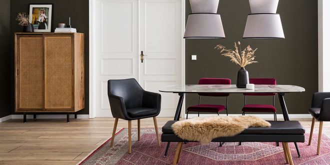 Wohnzimmer mit einem Marmortisch, einem Ledersessel, einer Rattankommode und roten Samtstühlen.