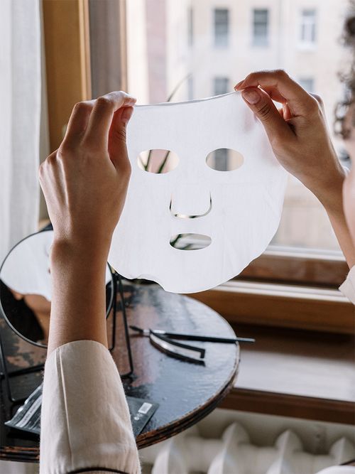 Frau hält Gesichtsmaske in der Hand.