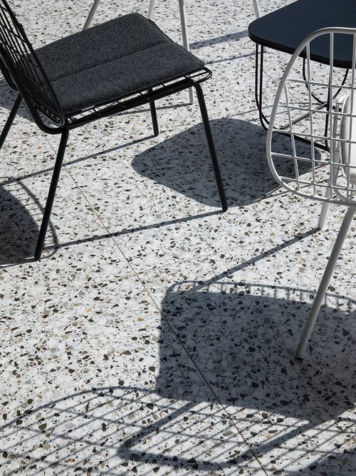 Ausschitt eines Terrazzobodens auf dem Metallstühle stehen.
