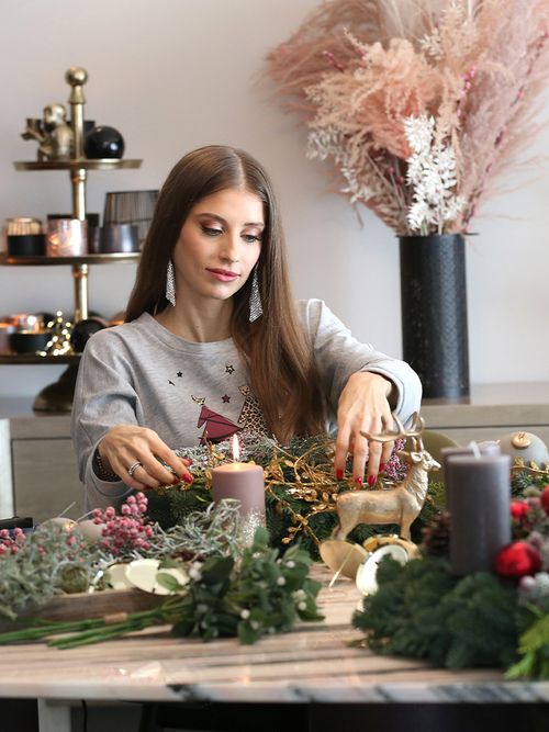 Kathy Hummels in einem grauen Weihnachtspullover die gerade einen Adventskranz bindet.