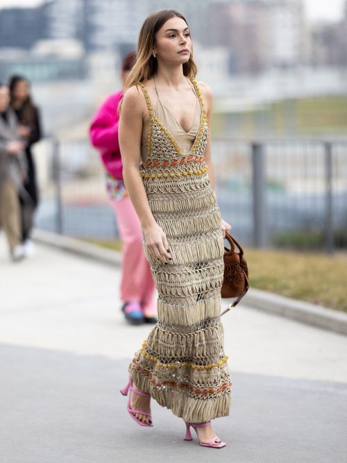 Street Style Look von der Milan Fashion Week, wo ein Gast ein beiges Häkelkkleid mit pinken Sandalen und brauner Tasche trägt.