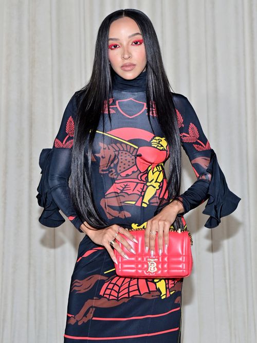 Tinashe trägt ein buntes Kleid mit roter Tasche und rotem Lidschatten auf einem Burberry Event in Los Angeles.