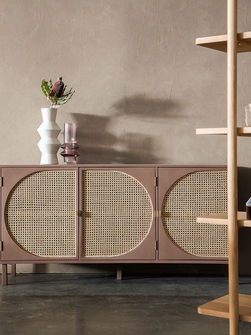 Rosa Sideboard mit Rattan vor einer beigen Wand.