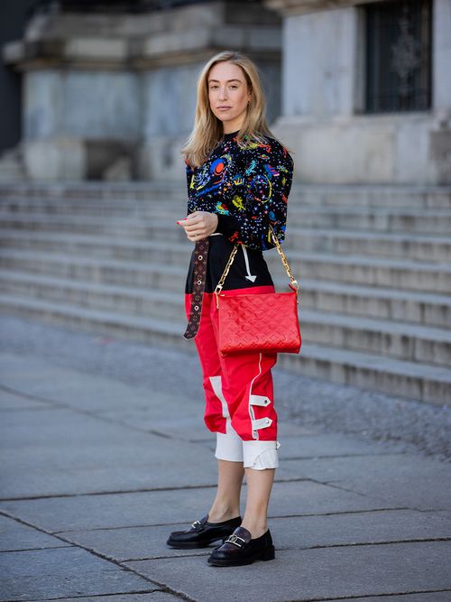Sonia Lyson in schwarzen Loafers und einer roten Tasche von Louis Vuitton.