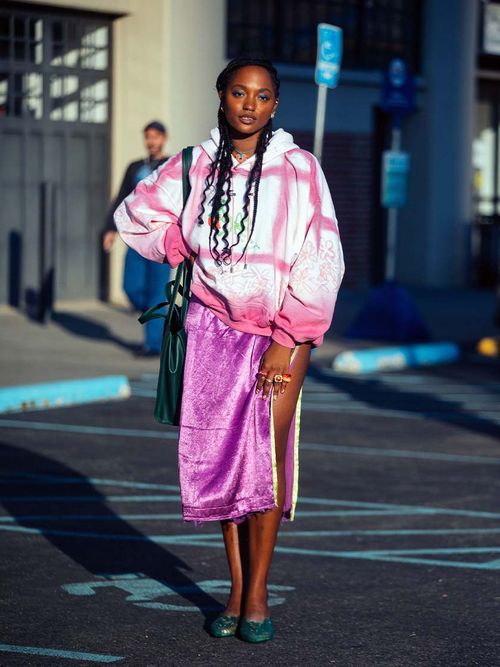 Streetstyle mit einem pinken Satinrock und einem pinken Batikpullover.