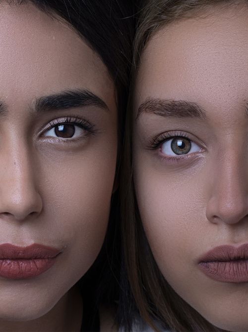 Close up von zwei Frauen, die ihre Gesichter aneinanderhalten und einen roten Lippenstift tragen.